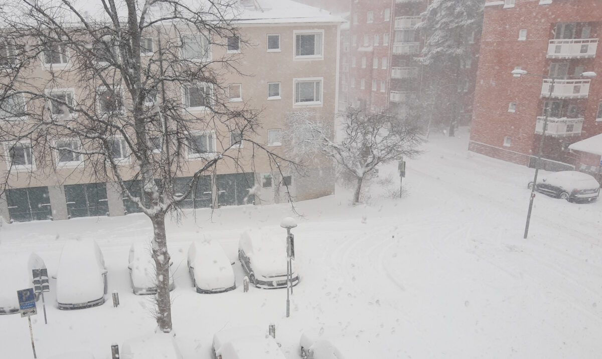 Parkering med insnöade bilder, en gata full med snö och snö i luften.