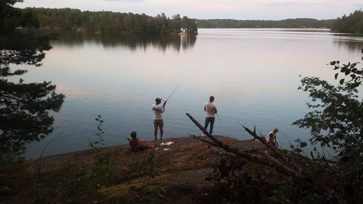 Killar som fiskar vid en insjö.